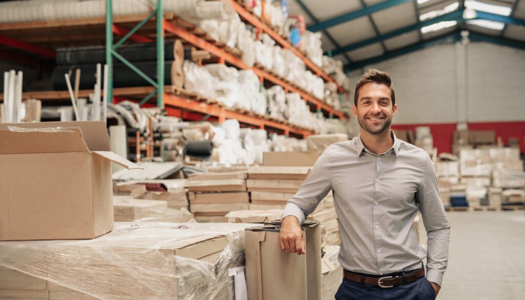 Portrait,Of,A,Smiling,Warehouse,Manager,Leaning,Against,Some,Stock
