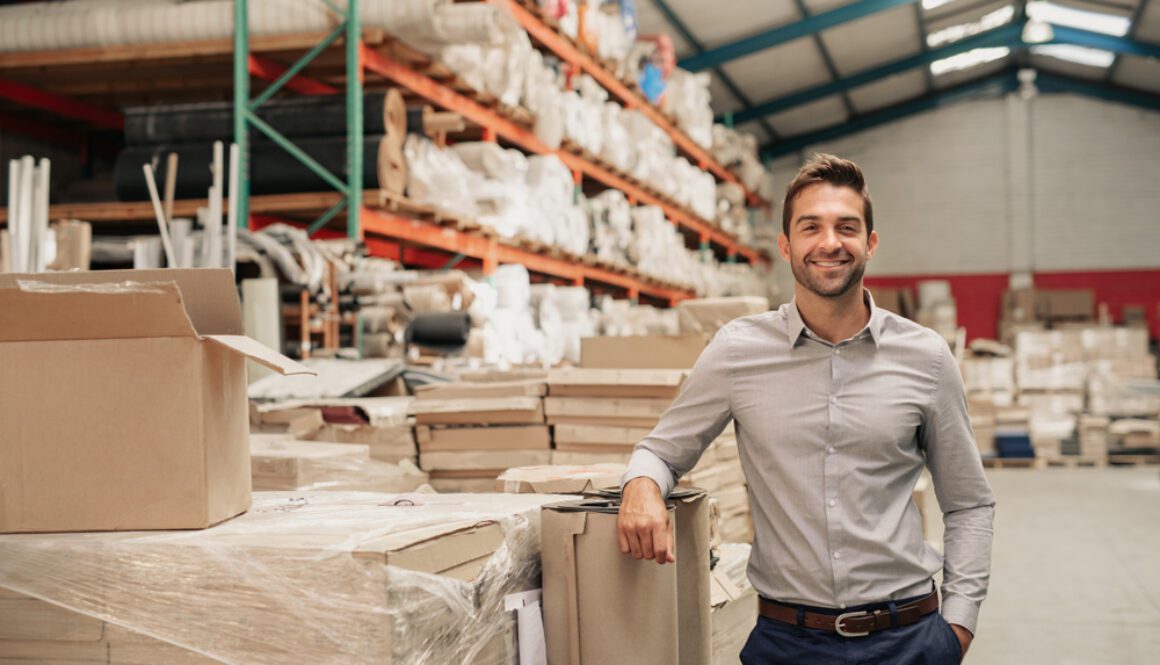 Portrait,Of,A,Smiling,Warehouse,Manager,Leaning,Against,Some,Stock