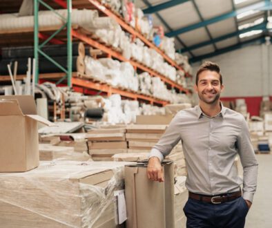 Portrait,Of,A,Smiling,Warehouse,Manager,Leaning,Against,Some,Stock